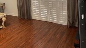 A room with a wooden floor, a large sliding door with blinds, and a small table with a decorative top. - Lovely 2-bedroom condo in Phoenix with WiFi and AC (Phoenix)