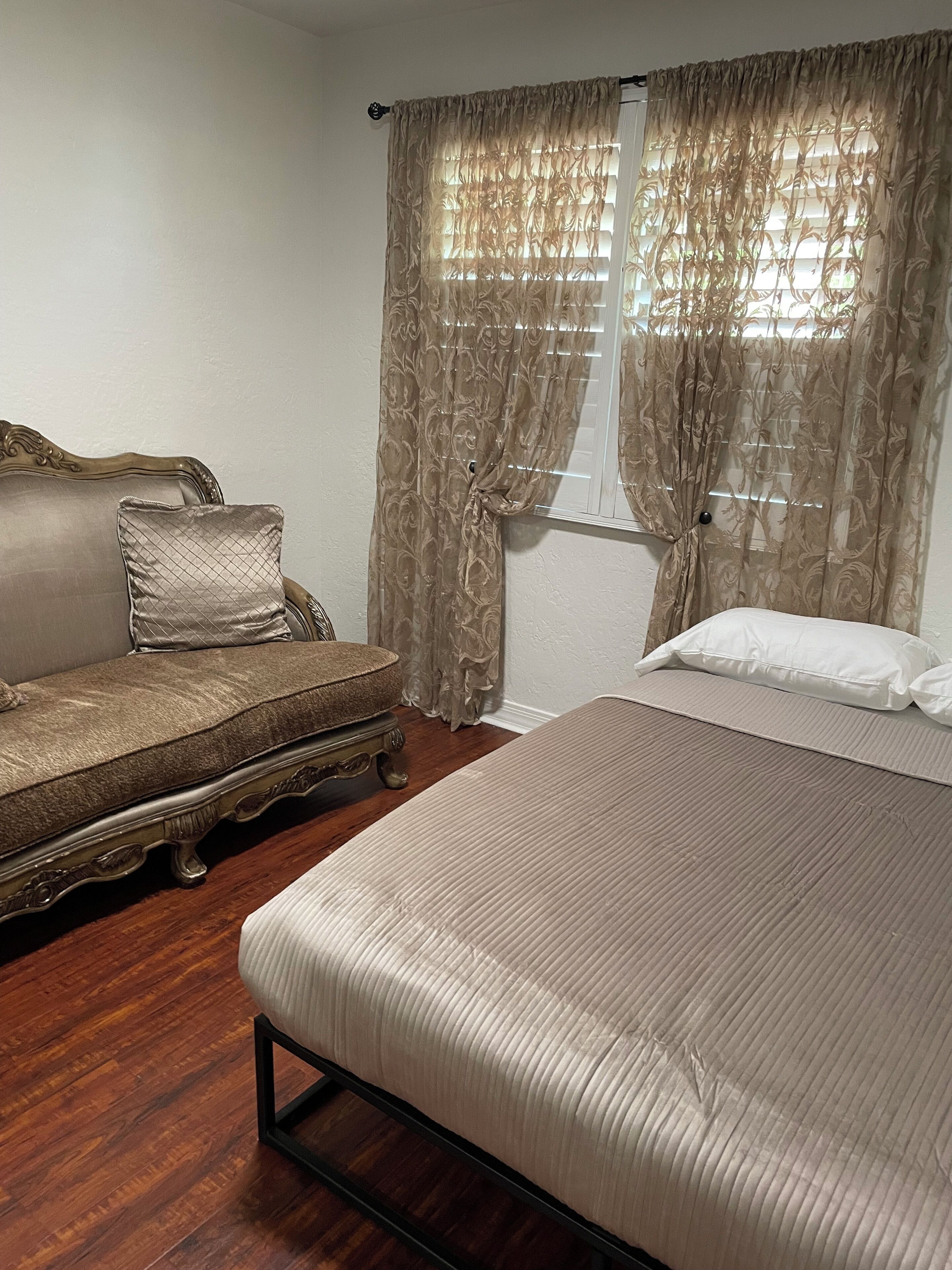 A bedroom with a bed, a sofa, and curtains.