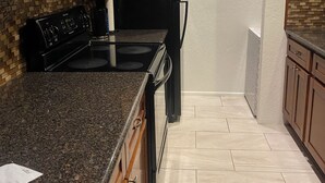 A kitchen with granite countertops, a black stove, and wooden cabinets. - Lovely 2-bedroom condo in Phoenix with WiFi and AC (Phoenix)