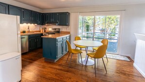 A kitchen with dark cabinets, a central island, and a dining area with yellow chairs.