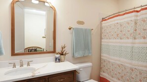 A bathroom with a white sink, a mirror, a toilet, and a shower curtain. - The Red Mountain Suite @ HSRV (Ivins)