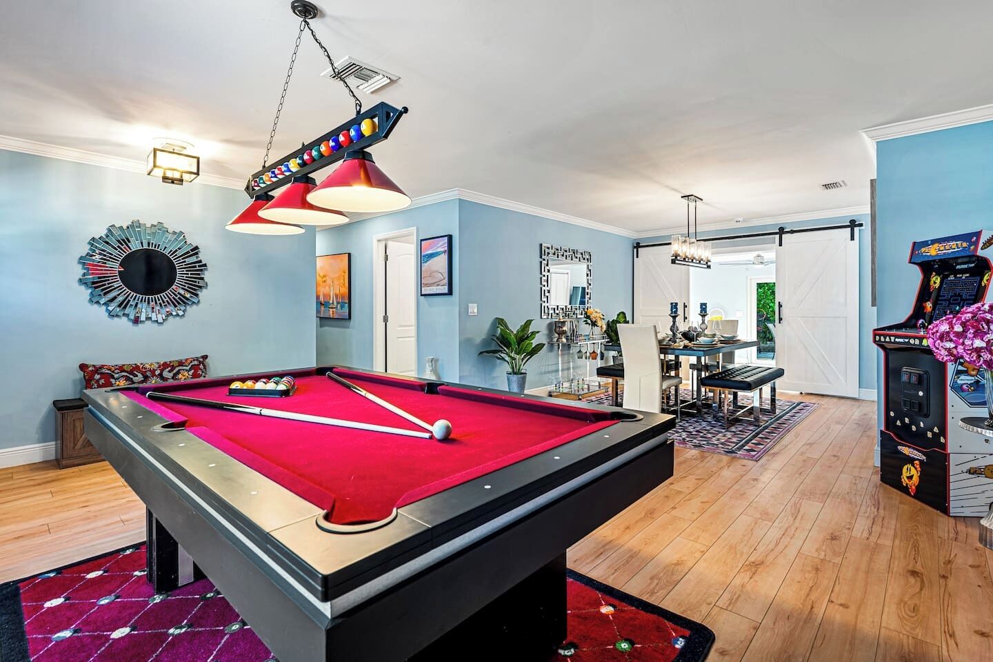 A pool table in a room with a dining area, a mirror, and a jukebox.