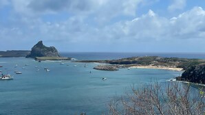 A coastal view with boats, rocky outcrops, and a clear sky. - Pousada Visual de Noronha (Fernando de Noronha)