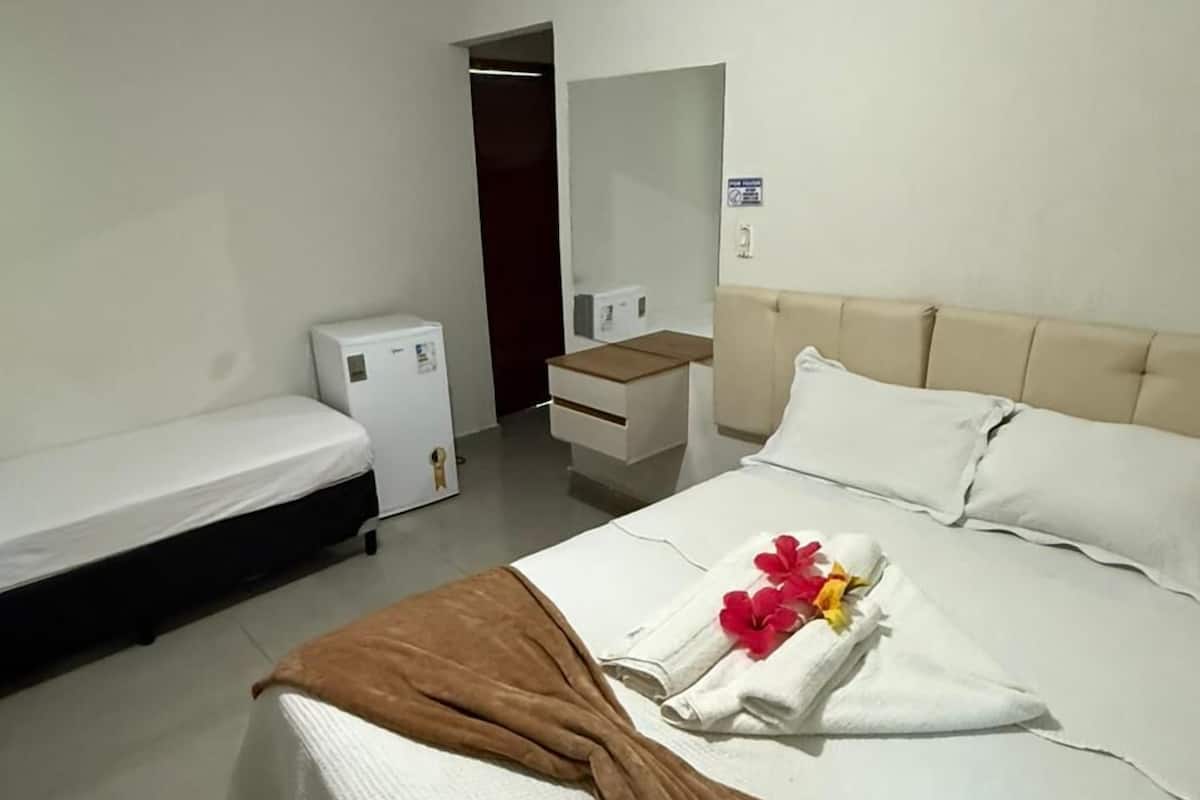 A hotel room with a bed, a small bedside table, a mirror, and a wardrobe.