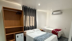 A bedroom with a bed, a wardrobe, a desk, and an air conditioning unit. - Pousada Visual de Noronha (Fernando de Noronha)