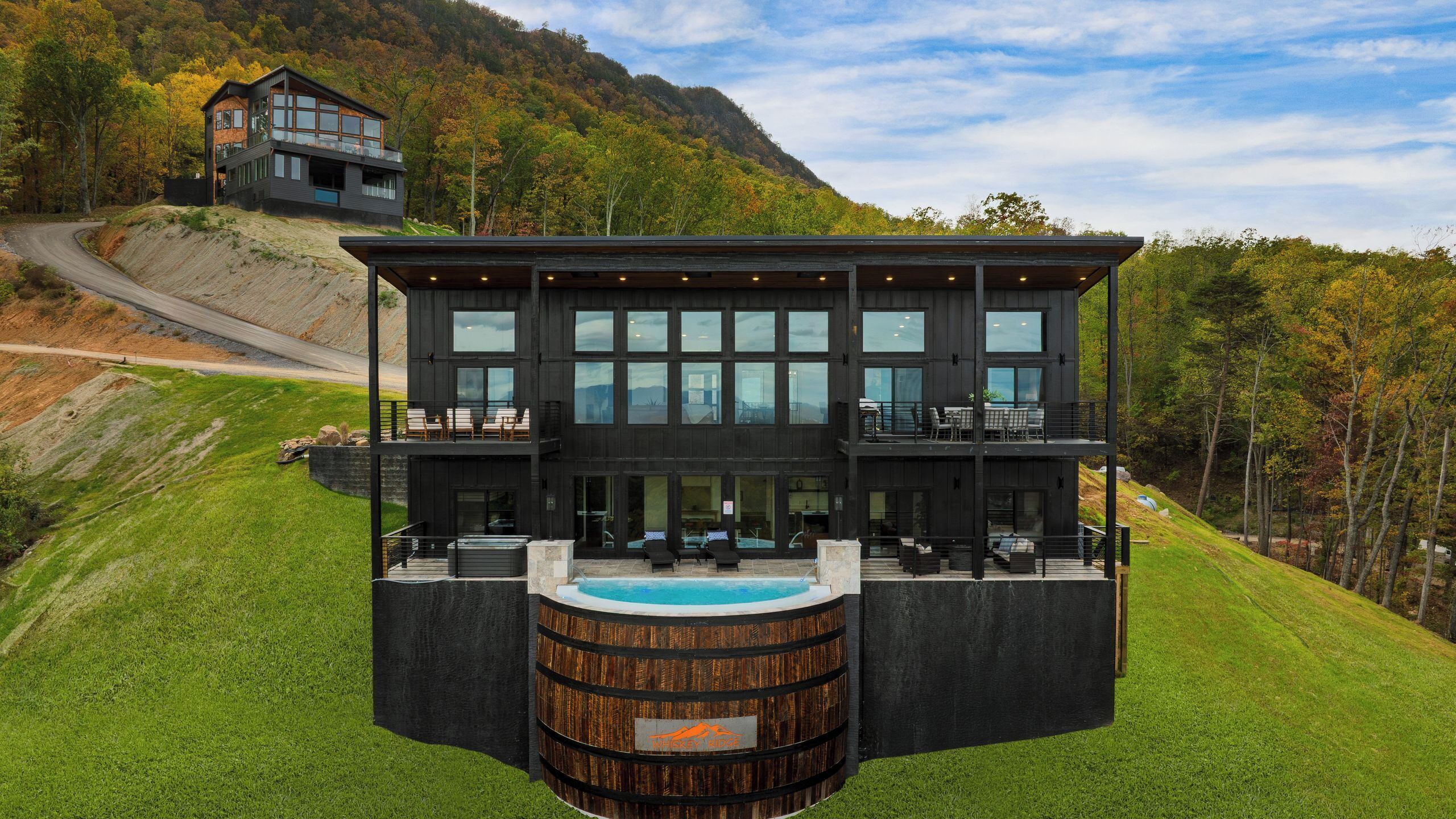 Ein modernes, zweistöckiges Gebäude mit Pool, umgeben von üppiger, grüner Landschaft und einem Berg im Hintergrund.