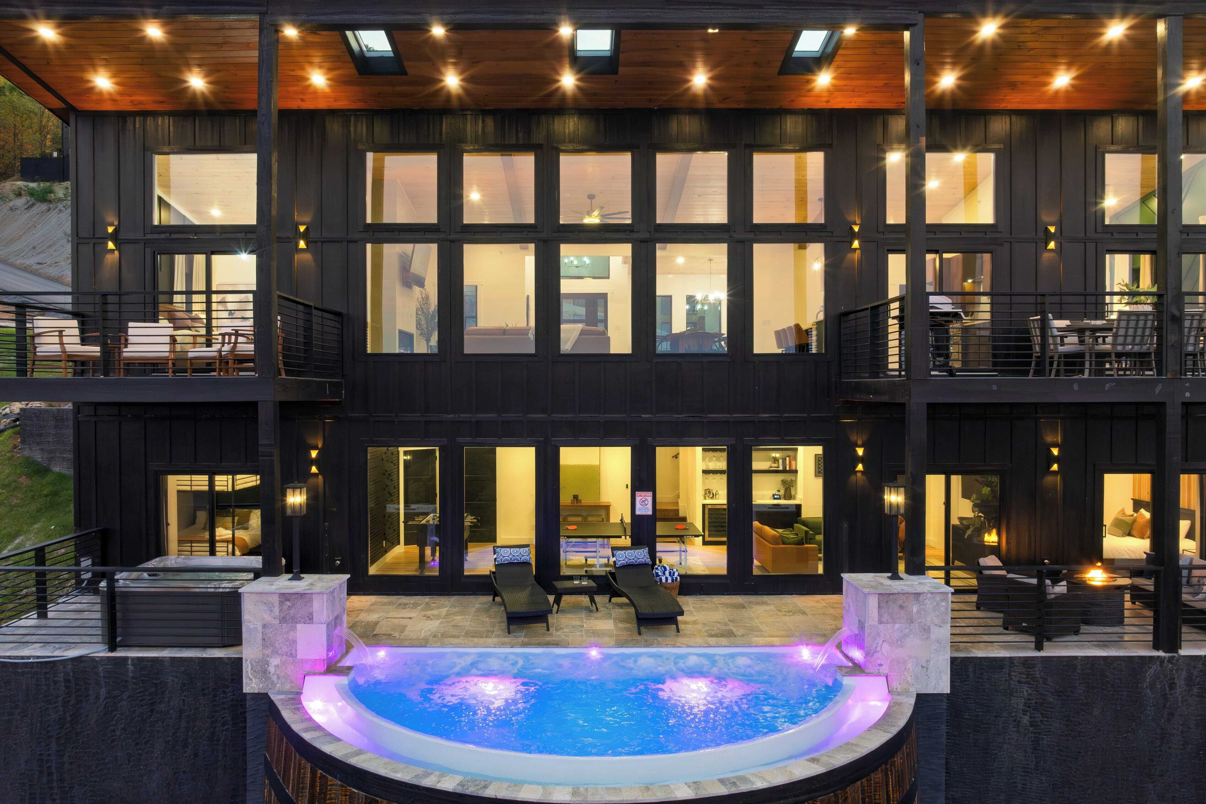 A two-story building with a large outdoor hot tub, multiple seating areas, and a well-lit interior.