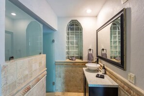 Bathroom features a large mirror, sink, and glass-enclosed shower area.