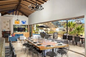 Relax in this open-plan living area with a dining table for six, a large TV, and a balcony with outdoor seating offering views of the surrounding area.