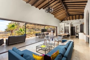 Relax in this stylish space with a sofa, dining area, and kitchen, offering a view of the outdoor patio and grill.
