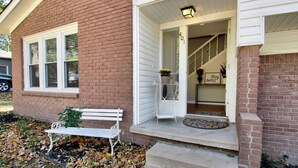 A brick house with a white front door, a bench outside, and a staircase leading to the entrance. - "Broken Arrow 3-Bedroom Retreat – Cozy, Family-Friendly with WiFi & AC!" (Broken Arrow)