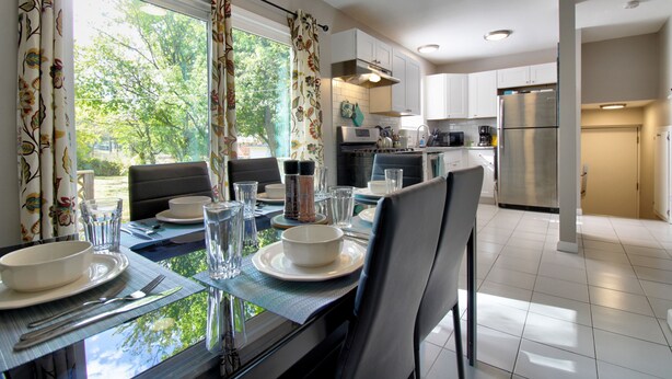 A modern kitchen with white cabinets, stainless steel appliances, and a dining area with a table set for two. - "Broken Arrow 3-Bedroom Retreat – Cozy, Family-Friendly with WiFi & AC!" (Broken Arrow)