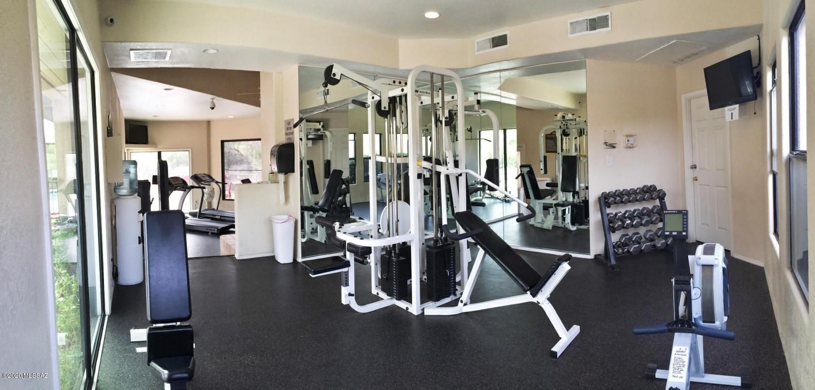 Une salle de sport équipée de divers appareils d’exercice, notamment un banc de développé couché, des haltères et un appareil de rame.