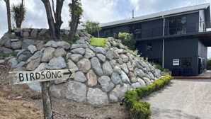 A stone wall with a wooden sign reading "Birdsong" pointing to the right. - ESCAPE TO THE COUNTRY (Kaitake)