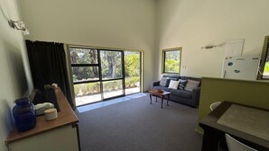 A room with a sofa, a small table, a window, and a door. - ESCAPE TO THE COUNTRY (Kaitake)