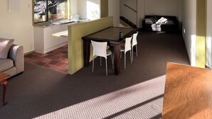 A spacious living area with a dining table and chairs, a sofa, and a kitchen area with a window. - ESCAPE TO THE COUNTRY (Kaitake)