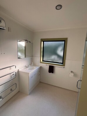 A bathroom with a white sink, mirror, and window. - ESCAPE TO THE COUNTRY (Kaitake)