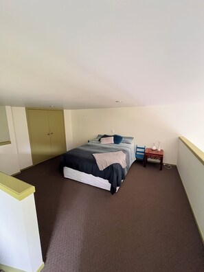 A bedroom with a bed, a nightstand, a chair, and a wardrobe. - ESCAPE TO THE COUNTRY (Kaitake)