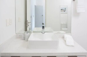 Um banheiro moderno com um espelho grande, uma pia retangular e um vaso sanitário.