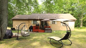Une maison avec une véranda, une chaise suspendue et une table à manger.
