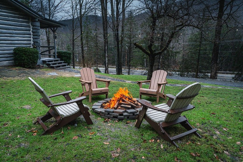 Een vuurplaats met vier Adirondack-stoelen eromheen, in een gazon.