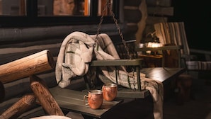 Un rincón exterior acogedor con un banco de madera, una mesa y un farol colgante.