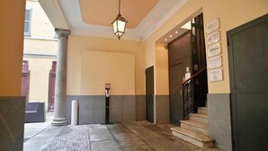 A hotel lobby with a stone floor, a large column, a staircase, and a door with a sign above it. - Centro Corso Venezia - Chic & Quiet Apartment in M (Milan)