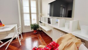 A modern living room with a flat-screen TV, white furniture, a potted plant, and a window. - Centro Corso Venezia - Chic & Quiet Apartment in M (Milan)