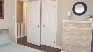 A bedroom with a bed, a dresser, and two white doors.