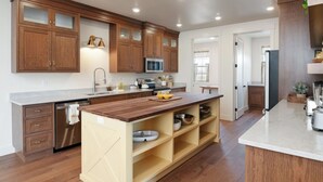 A modern kitchen with wooden cabinets, a central island, stainless steel appliances, and a marble countertop. - The South Hills Suite @ HSRV  (Ivins)