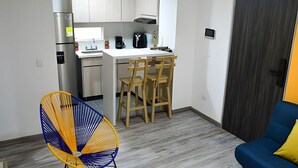 Une cuisine de taille réduite, équipée d’un réfrigérateur, d’une cuisinière et de chaises en bois.