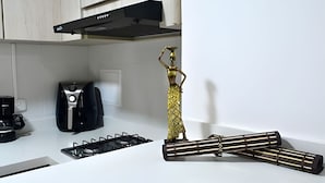 Une cuisine équipée d’une cuisinière à gaz, d’une machine à café et d’une statuette décorative en or.