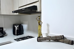 A kitchen with a gas stove, a coffee machine, and a decorative golden figure.