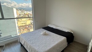 A bedroom with a large window, a bed, and a view of a cityscape. - Spacious and Luxurious -Stratum 6 (Manizales)