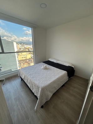 A bedroom with a large window, a bed, and a view of a cityscape. - Spacious and Luxurious -Stratum 6 (Manizales)