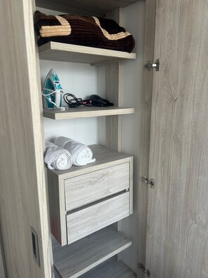 A wardrobe with a hanging shelf, a folded towel, and a pair of shoes. - Spacious and Luxurious -Stratum 6 (Manizales)