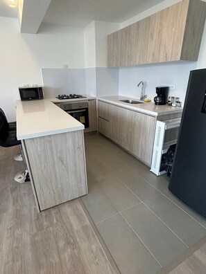 A modern kitchen with a built-in microwave, stove, and sink. - Spacious and Luxurious -Stratum 6 (Manizales)