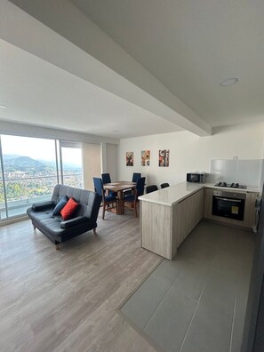 A modern apartment with a dining area, a kitchen, and a large window offering a city view. - Spacious and Luxurious -Stratum 6 (Manizales)