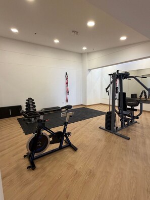 Une salle de sport équipée de matériel d’exercice, d’un miroir et d’un élastique de résistance fixé au mur.