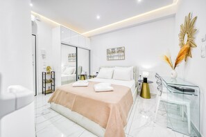 Une chambre à coucher moderne avec un grand lit, une table de chevet en verre, un miroir et un élément décoratif mural.