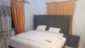 Une chambre à coucher avec un lit, des rideaux et une table de chevet.