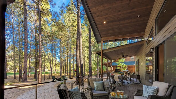 Un espace extérieur aménagé avec des meubles en osier, une table avec des boissons et une vue sur une zone boisée.