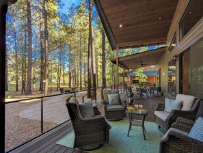Un espace extérieur aménagé avec des meubles en osier, une table avec des boissons et une vue sur une zone boisée.