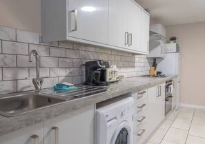 Una cocina moderna con lavadora integrada, un lavamanos y un tostador.