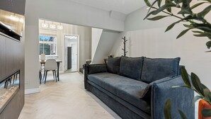 A modern living room with a sofa, a dining area, and a kitchen. - 29 Carleton Street · Newly Refurbished 2-Bed Terraced Home in York - Pass the Keys (York)