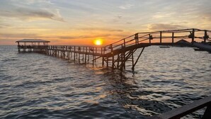 Een steiger die zich uitstrekt in rustig water bij zonsondergang.