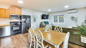 A compact kitchen with a dining table, chairs, a microwave, a refrigerator, and a TV mounted on the wall. - Lake-View Home in Statham w/ On-Site Fishing (Statham)