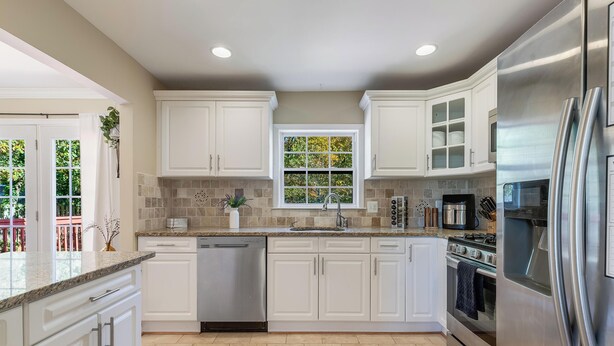 Una cocina moderna con armarios blancos, un refrigerador de acero inoxidable y un lavavajillas.