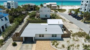 Ein Anwesen direkt am Strand mit einem Bungalow, einer überdachten Terrasse und einem Parkplatz.