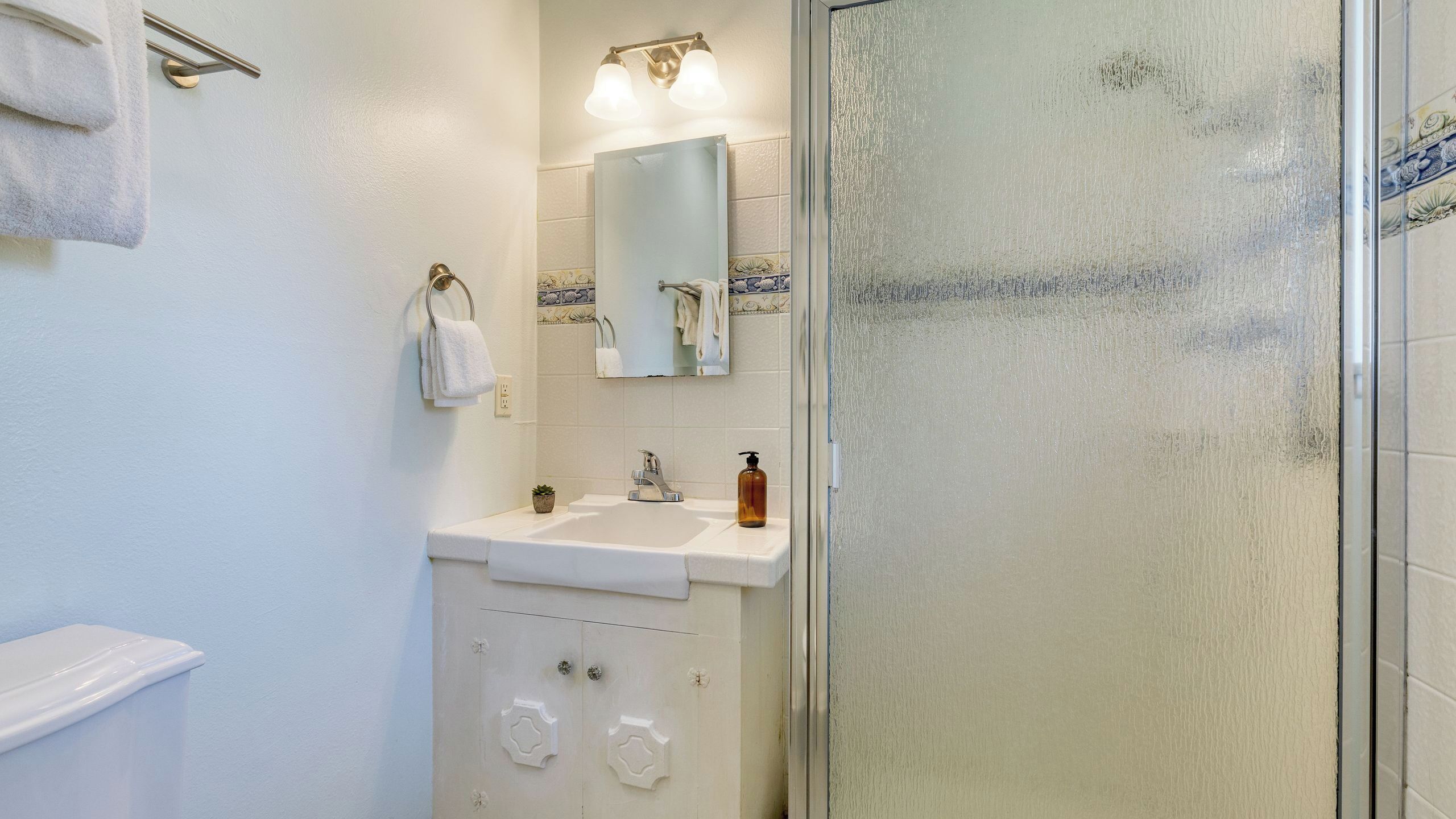 A bathroom with a sink, mirror, and shower.